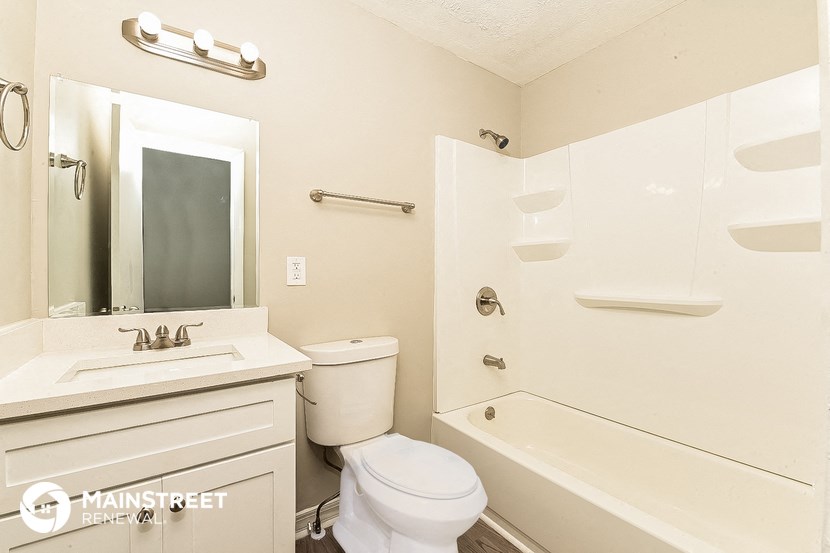 a bathroom with a toilet sink and tub and a mirror