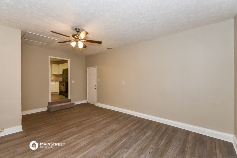 the living room of an empty house with a ceiling fan