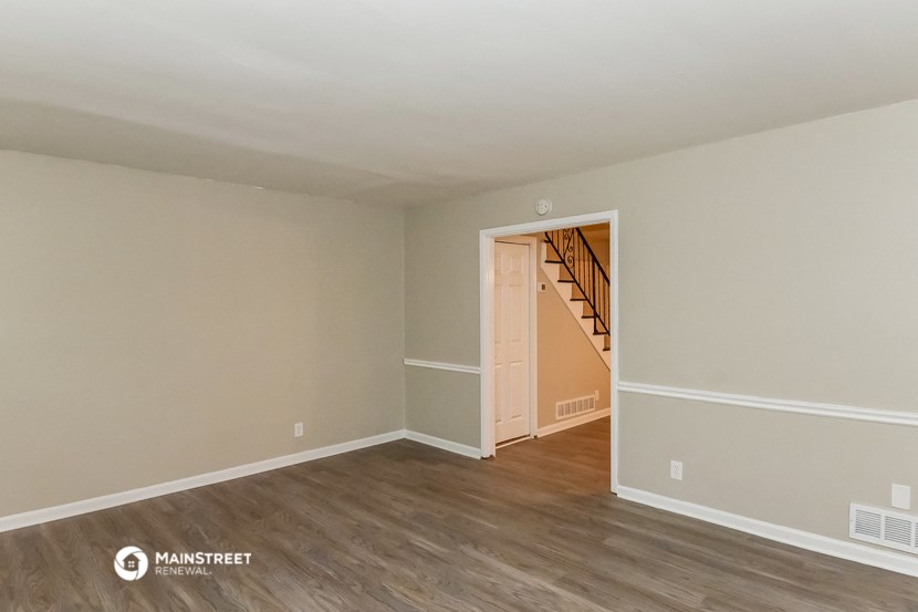 the living room of an apartment with wood flooring and a staircase
