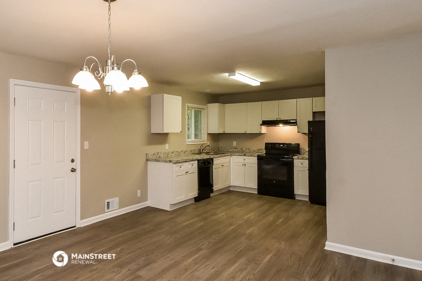 an empty kitchen with white cabinets and black appliances