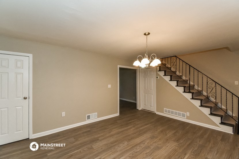 the living room of a house with a staircase and a white door