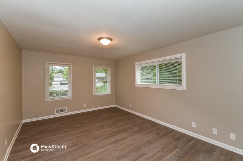 the spacious living room with hardwood flooring and two windows