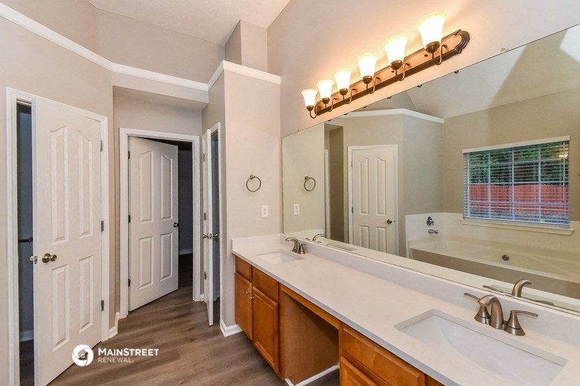 the master bathroom has a large vanity mirror and a large sink