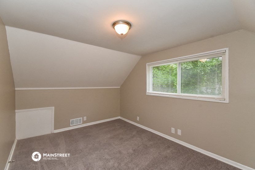 the bedroom of a house with a large window and carpet