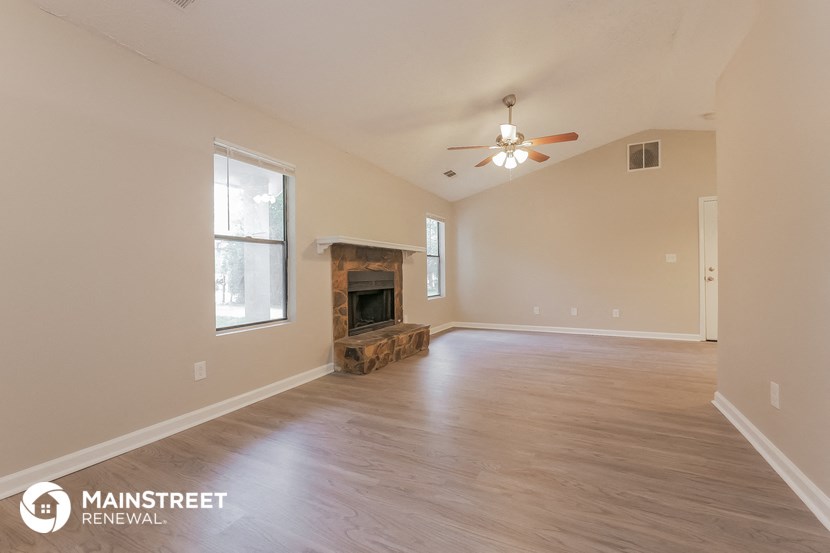 a living room with a fireplace and a ceiling fan