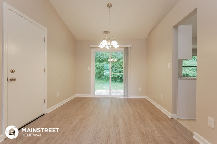 the spacious living room with wood flooring and a doorway to the backyard