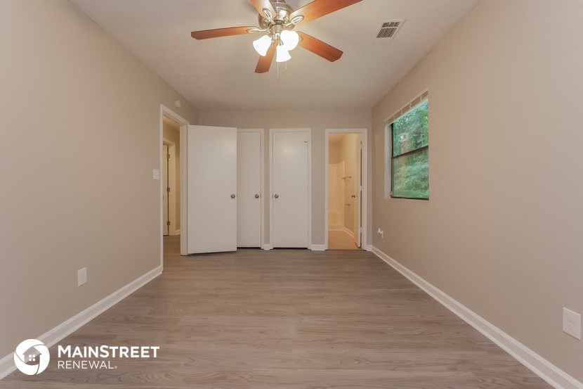 the spacious living room has a ceiling fan and hardwood floors