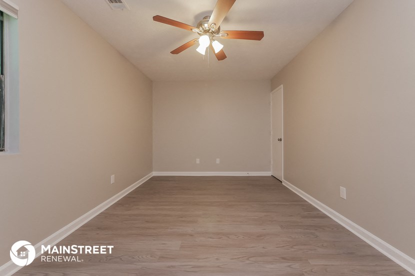 the spacious living room with ceiling fan and wood flooring