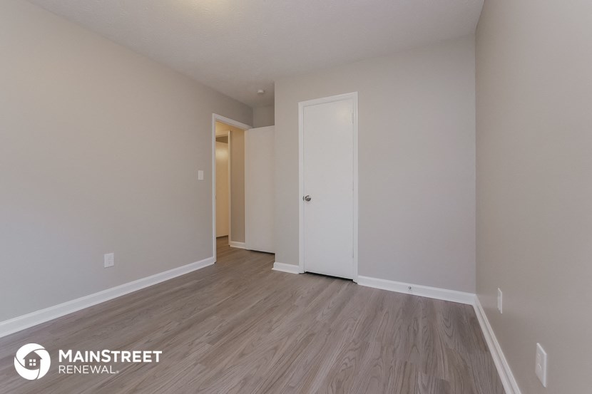 the spacious living room with wood flooring and white walls