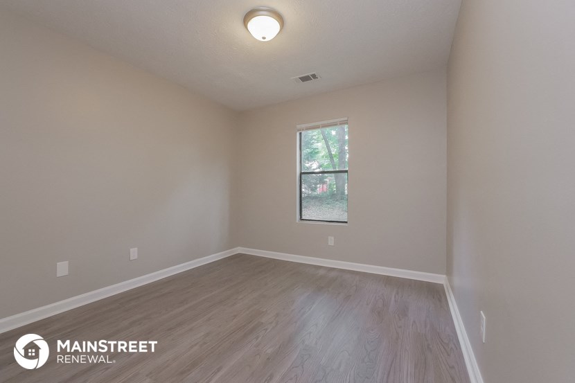 the interior of an empty room with wood flooring and a window