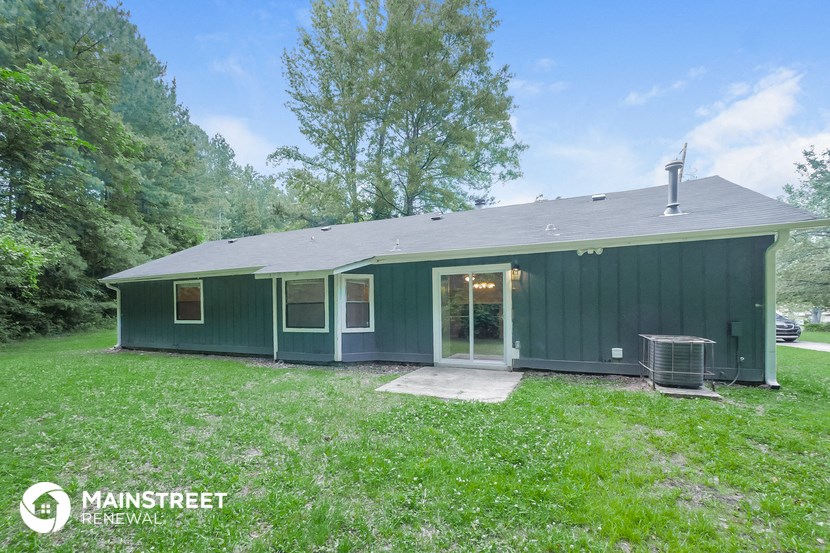 the exterior of a green house with a yard and a grill