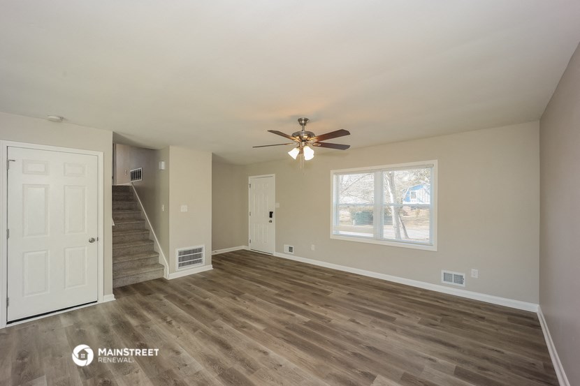 the living room of an empty house with a ceiling fan