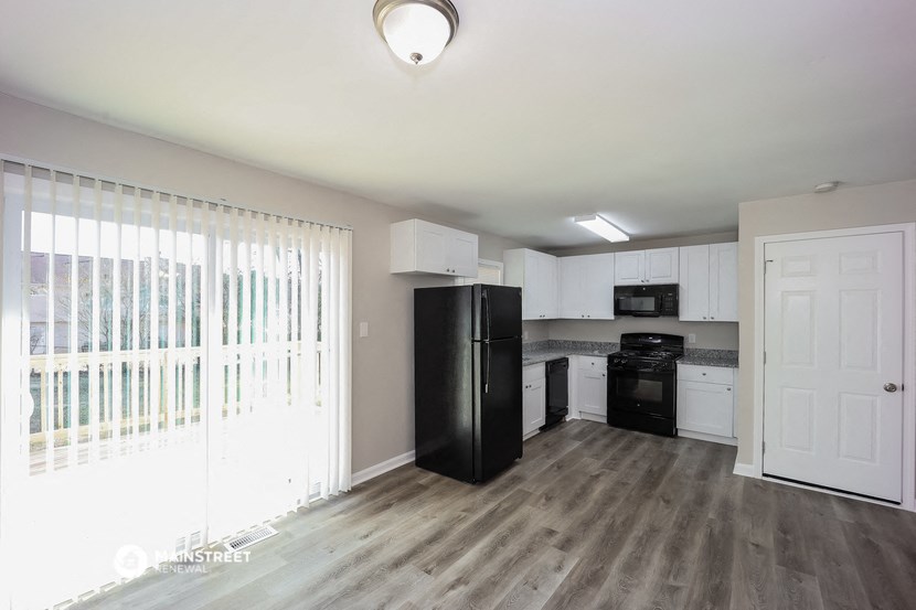 an empty kitchen with white cabinets and a black refrigerator