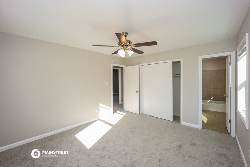 an empty living room with a ceiling fan and a closet