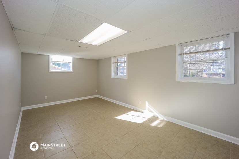 an empty living room with two windows and a tiled floor