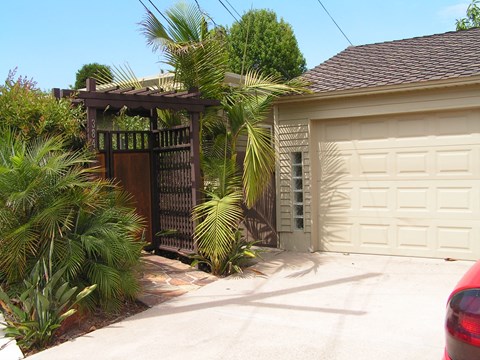 A house with a white garage door and a brown pergola.
