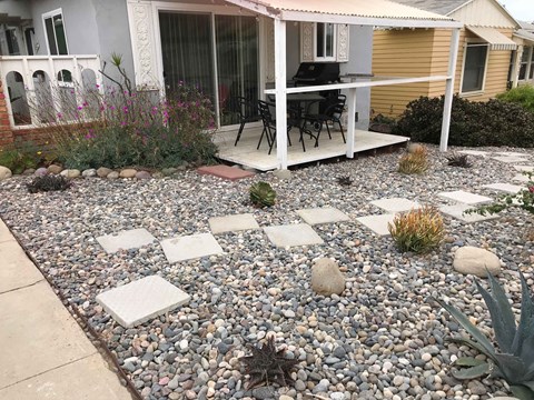 A patio with a table and chairs is surrounded by a gravel area with stepping stones.