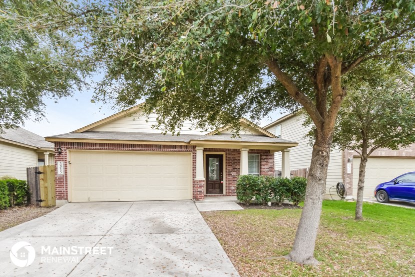 a small white house with a driveway and a tree