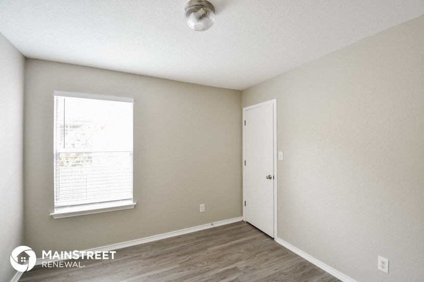 the spacious living room with a large window and wood flooring