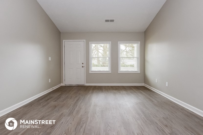 the spacious living room with wood floors and white walls