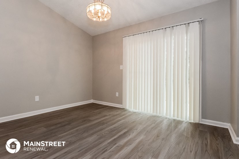 the spacious living room with white blinds and wood flooring