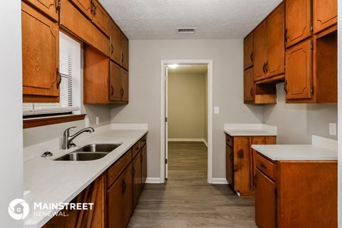 a kitchen with wooden cabinets and white counter tops and a sink