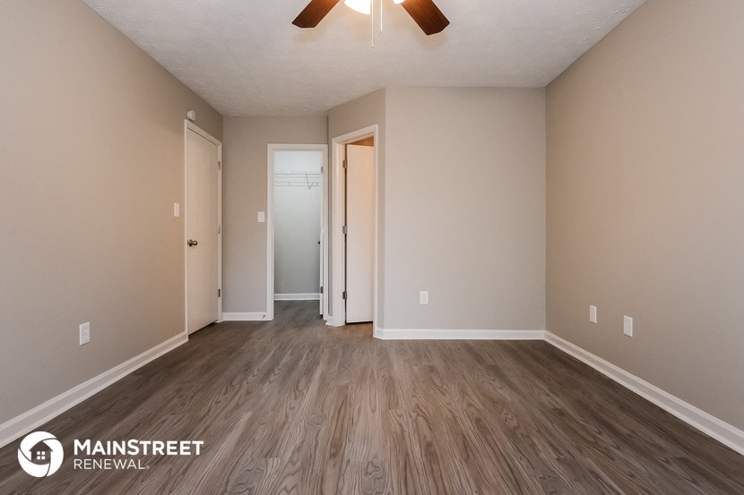 the spacious living room with wood flooring and a ceiling fan