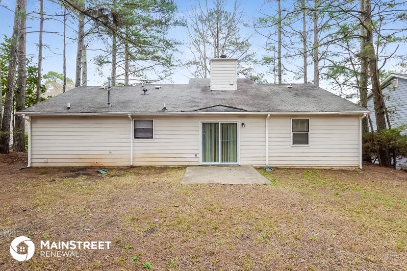 the front of a white house with a yard and trees