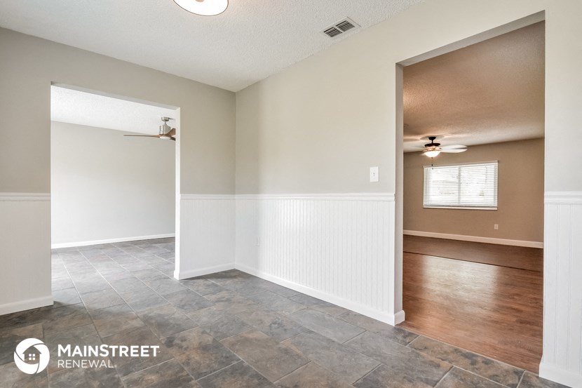 the living room and dining room with white walls and wood flooring