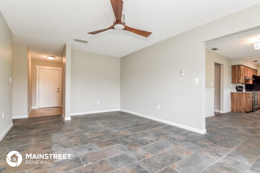 a living room with a ceiling fan and a kitchen