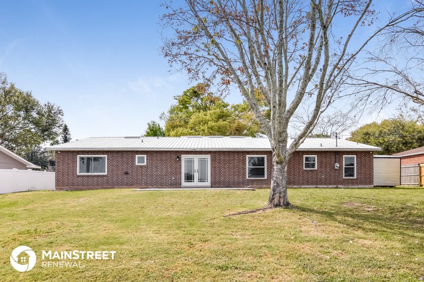 a small brick house with a tree in the yard