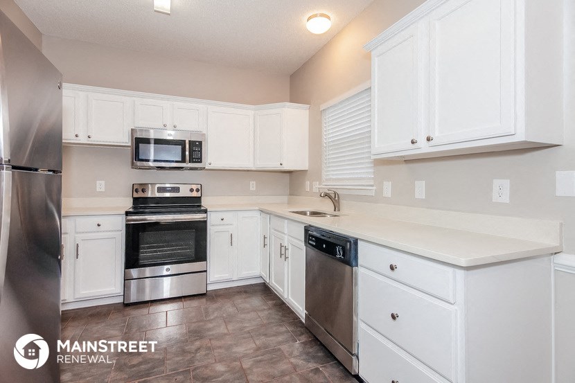 a white kitchen with stainless steel appliances and white cabinets