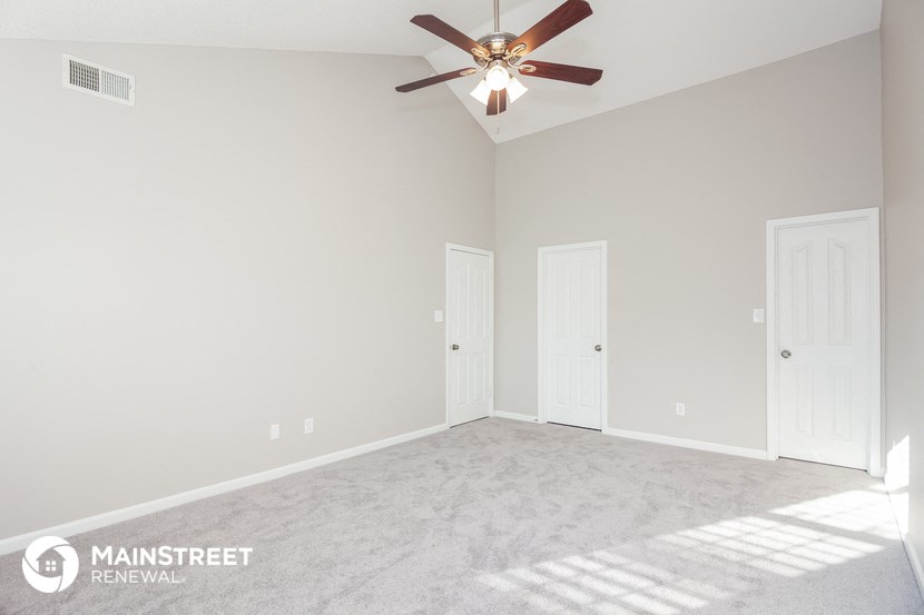 an empty room with a ceiling fan and white doors