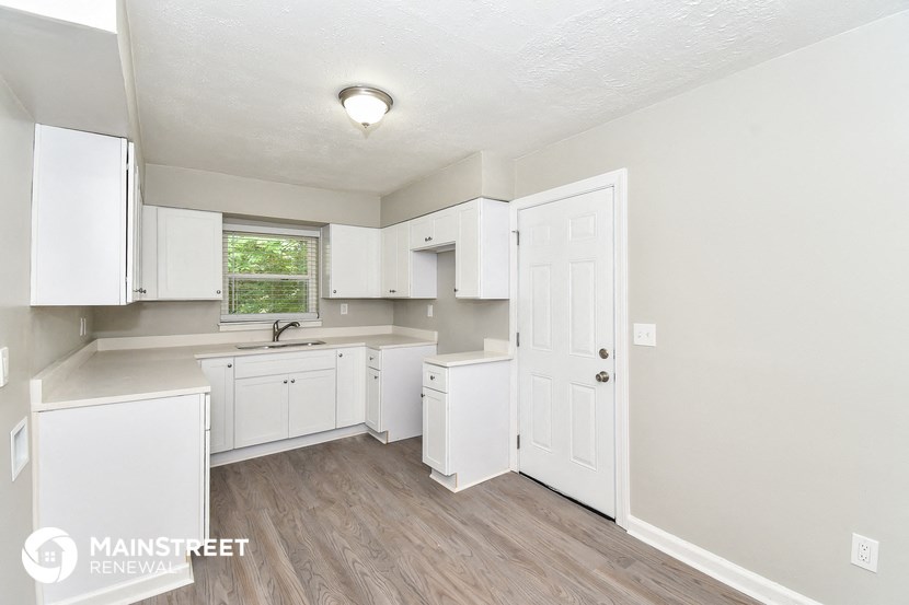a white kitchen with white cabinets and a window