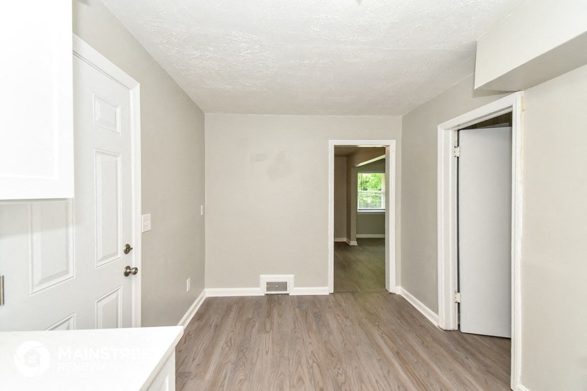 an empty living room and hallway with white walls and wood floors