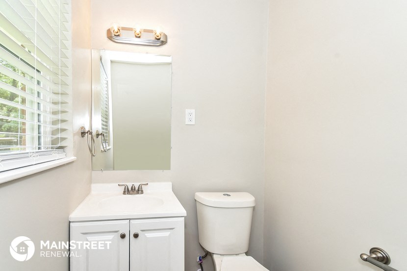 a bathroom with a toilet sink and mirror and a window