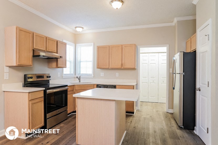 an empty kitchen with wooden cabinets and a black refrigerator