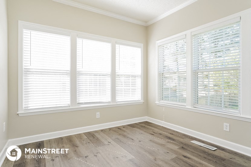 the living room of a home with a wood floor and large windows