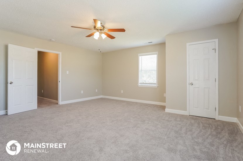 the living room of an empty house with a ceiling fan