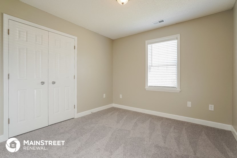 the bedroom of a home with carpet and a white door