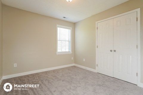 the living room of a home with a white door and carpet