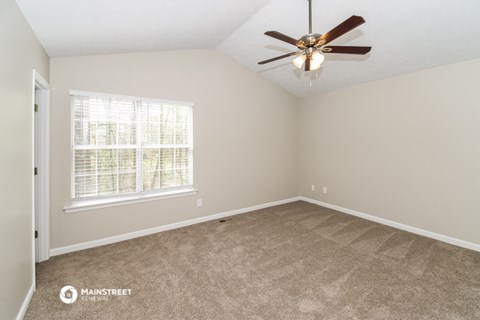 the spacious living room with carpet and a ceiling fan