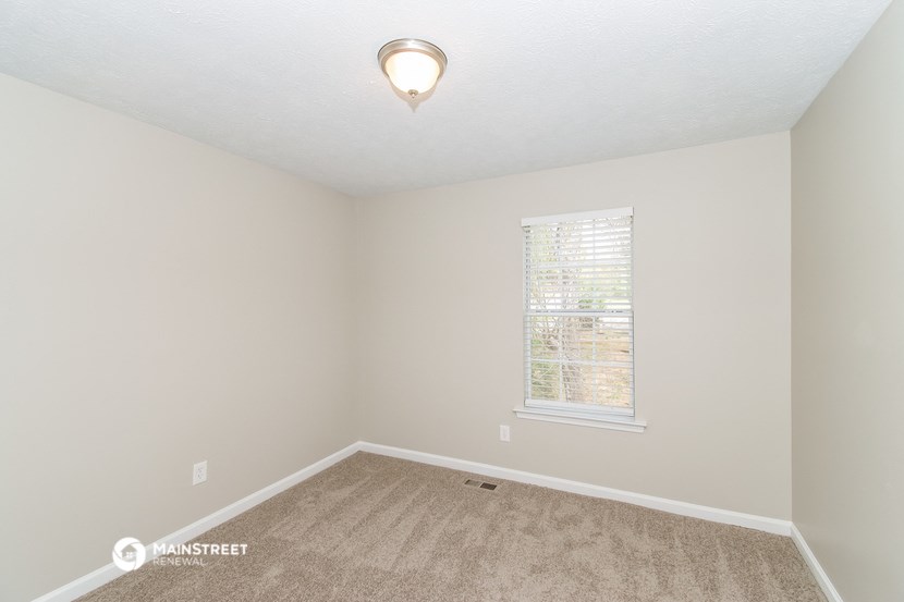 the spacious bedroom with carpet and a window
