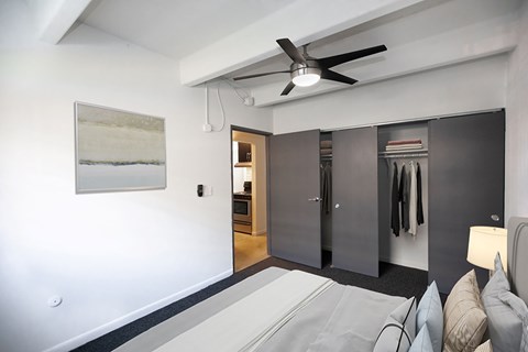 a bedroom with a bed and closet and a ceiling fan