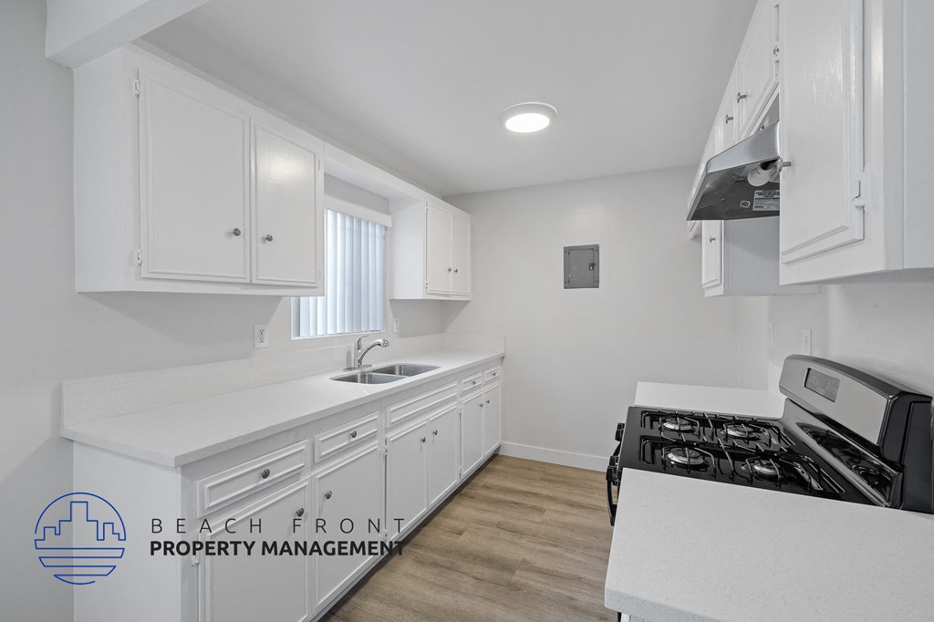 a white kitchen with white cabinets and white counter tops and a black stove top oven