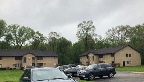 a parking lot filled with cars in front of two buildings