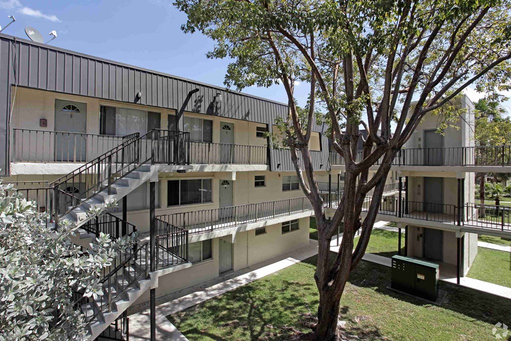 the exterior of an apartment building with stairs and a tree