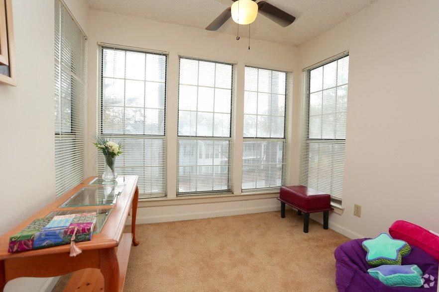 a living room with four windows and a table and a chair