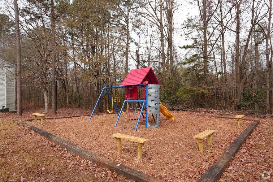 a playground with a red swing set and benches
