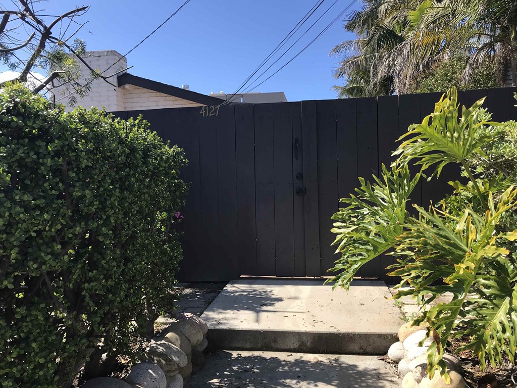 a black fence in a backyard with a pathway and plants